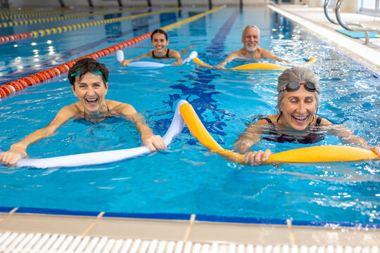 Group of people working with float noodles at water fitness class