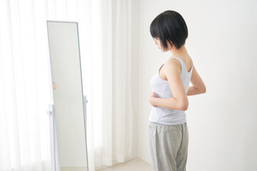 鏡で体型をチェックする女性 - obrazy, fototapety, plakaty