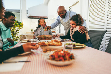 Happy african family eating lunch together at home terrace outdoor - Soft focus on daughter hand