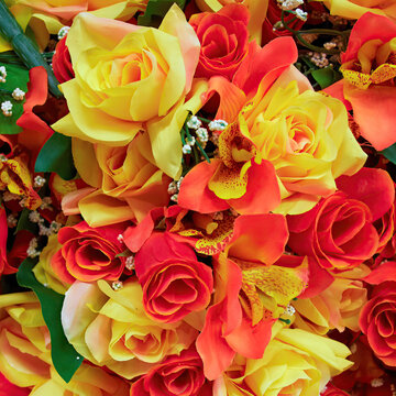 Bright orange and yellow artificial handmade roses bouquet, floral background.