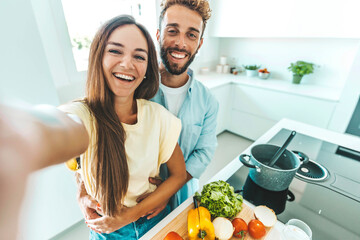 Young happy couple preparing healthy meal in kitchen at home - Husband and wife cooking salad -...