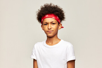 Angry frowning kid boy of 13 in red bandana and white mock-up t-shirt with blank copy space for your advertising content looking at camera with annoyed facial expression. I don't like it
