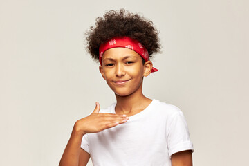 Studio image of confident african american male kid of 13 showing denial and refusal gesture with hand, giving sign about his attitude, wearing red bandana on gray background. Body language