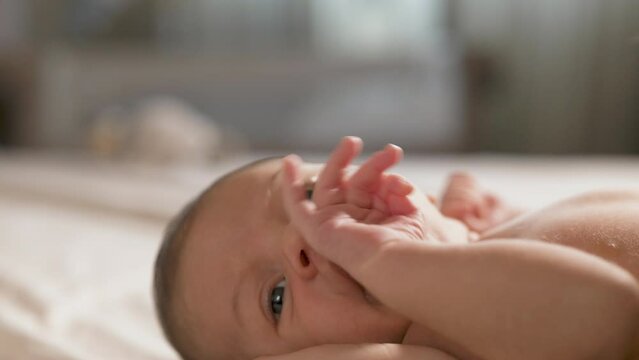 Slow Motion Portrait of New Born Baby Resting Peacefully in the Arms of his Mother as She Leens to Kiss him. Woman New to Motherhood Expressing her Unconditional Love to her Child and Bonding with Him