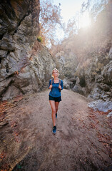 Fototapeta premium Active lifestyle. Trekking and hiking. Young woman with rucksack in the rocks forest.