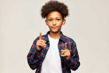 May i ask? Portrait of cute stylish african american male teenager pointing index fingers up as...