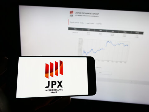 Stuttgart, Germany - 01-25-2023: Person holding mobile phone with logo of company Japan Exchange Group Inc. (JPX) on screen in front of business web page. Focus on phone display.
