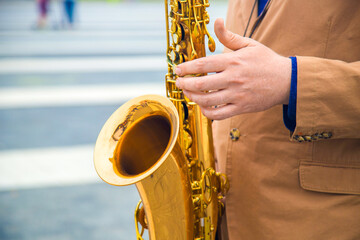 close-up of the hands of a  street musician playing the saxophone - obrazy, fototapety, plakaty