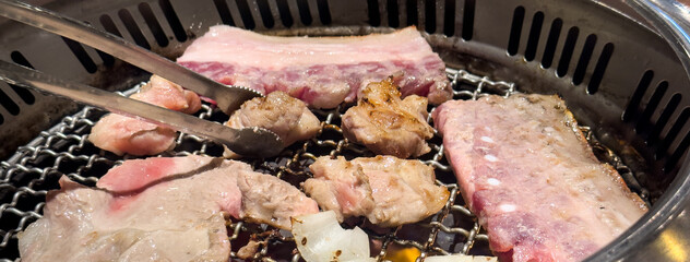 Grilling pork belly meat on a round BBQ net in restaurant for eating.