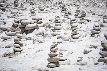 Fototapeta na wymiar View of hundreds of cairns, stacks of balanced white round stones, on the beautiful White Beach on Zakynthos, Greece