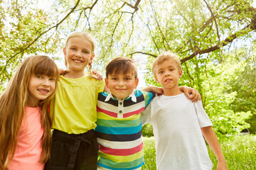 Happy group of children together in green garden in summer