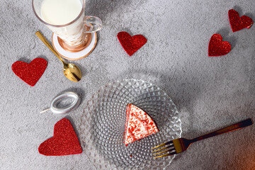 red velvet cake with red hearts and glass of milk on stone gray background with gold cutlery