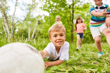Fototapeta premium Kid playing soccer with friends in park during vacation