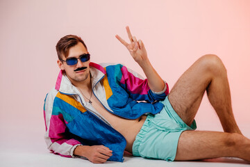 Back in time 90s 80s lifestyle concept. Studio footage of stylish cheerful young man in vintage retro jacket on light pink background, candy-colored fashions, creativity, emotions, facial expression