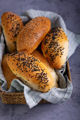 Loaves of Vienna bread covered with sesame seeds inside basket with blue tea towel