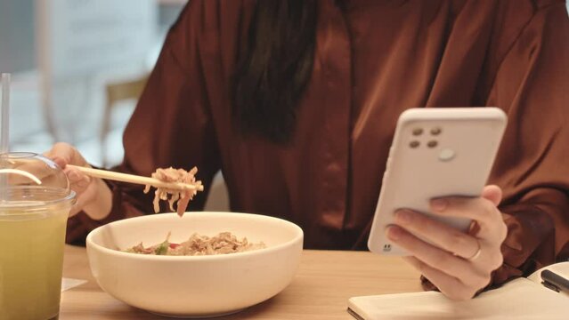 Cropped shot of unrecognizable woman using smartphone while having lunch in restaurant