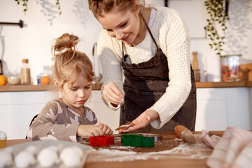 Happy family mother and little daughter  cooking  making sweet pastries on kitchen