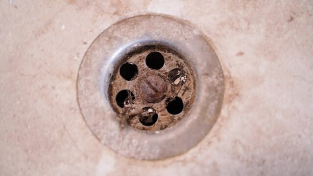 Dirty rusty bathroom drain close-up. Hair and dirt in the sink. Camera rotation around