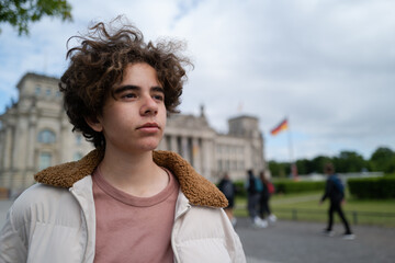 Portrait of a white teenager in front of the German parliament in Berlin on a cloudy day