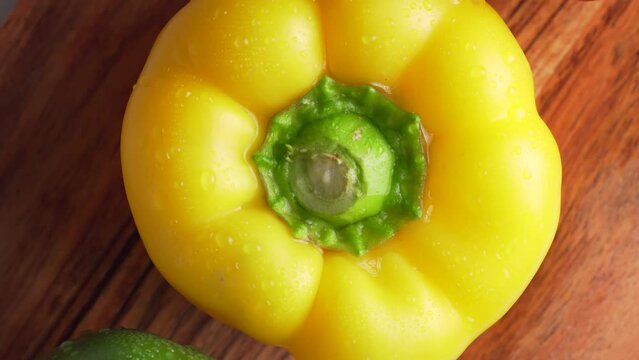 Yellow, red and green wet bell pepper rotated on wooden background, top view. Mixed fresh colorful Bell Peppers