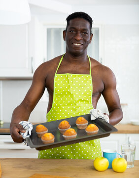 Man In Apron Holding Baking Sheet With Cupcakes