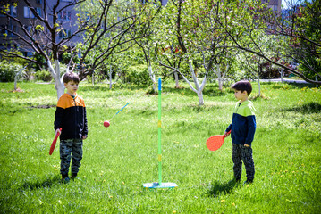 Fototapeta premium Two friends are playing tetherball swing ball game in summer camping. Two boy brother happy leisure healthy active time outdoors concept