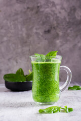 Fresh spinach smoothie in a glass and a bowl with leaves. Natural antioxidant. Vertical view