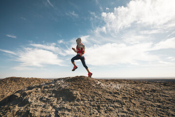 Woman trail runner cross country running on desert hill top