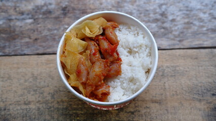 Rice bowl with spicy squid and potato chips. Nasi cumi asin 