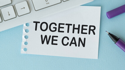 TOGETHER WE CAN text on a notebook paper on white blue background , business concept