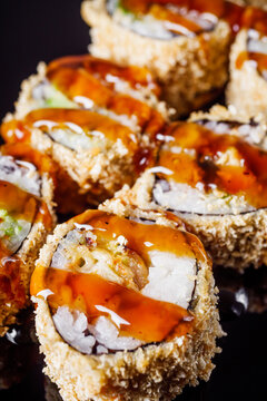 hot sushi roll tempura with eel shrimp crab salmon cream cheese cucumber avocado unagi on a black mirror background