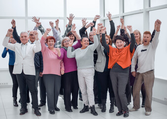 Happy group of people raising their hands to rejoice of victory