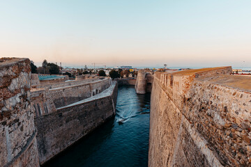 General view of the moat of the Royal Walls of Ceuta at sunset while a ship crosses it