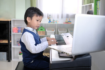 Adorable asian little boy learning music lesson at home. A kid studying piano online class with...