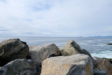 Fototapeta na wymiar Rocky coastline of the ocean bay, cloudy sky 