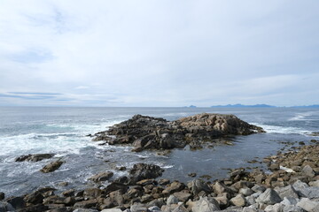 Fototapeta na wymiar Rocky coastline of the ocean bay, cloudy sky 