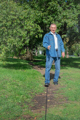 an elderly man walks with a dog in the park, holds a leash and laughs. The dog behind the scenes, selective focus