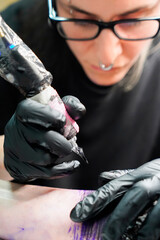 Close-up of a woman making a tattoo to another girl. Alternative art