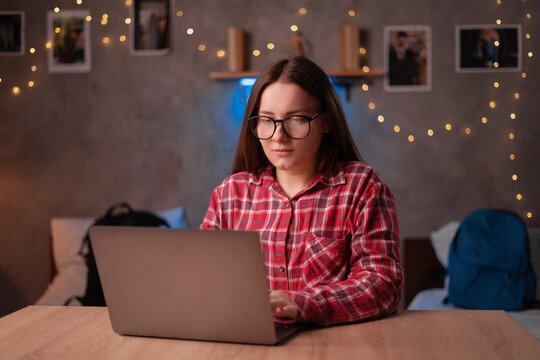 Portrait of young casual student working or studying using laptop computer at home office or in the student dormitory. Indoors image