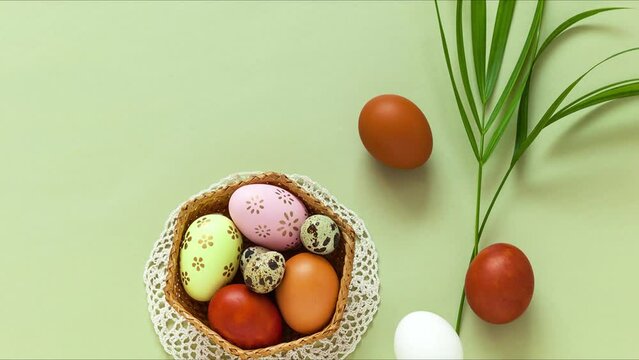 Easter spring still life with a green palm branch and painted Easter eggs on a pastel green background. Greeting message. Flat lay, close-up, top view, mock up
