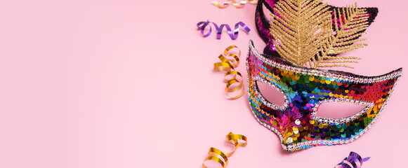 Festive face mask for carnival or masquerade celebration on colored banner background. Copy space