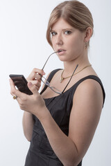 Young woman is using a calculator in front a bright white background and looks worried