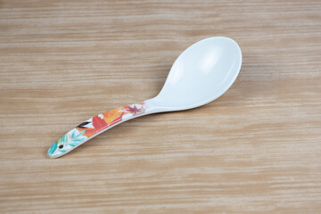 White plastic spoon on the wooden table 