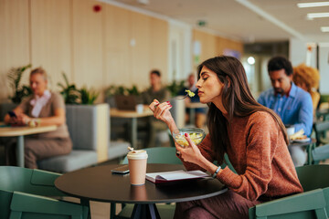Businesswoman eating lunch in company cafeteria.