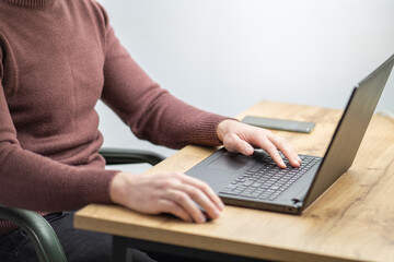 Close up of a man working on laptop at the office. Office worker hands typing on keyboard. Business man using laptop 