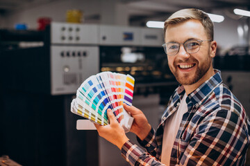 Man working in printing house with paper and paints