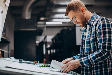 Obraz premium Man working in printing house with paper and paints
