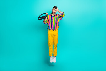Full body photo of funny guy wear striped retro shirt hold steering driving wheel touch head drunk accident isolated on aquamarine color background