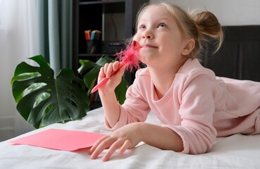 A child writes a valentine card on the bed with a pen with a heart. The concept for Valentine's Day...