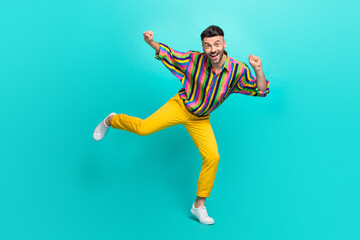 Full length photo of satisfied man dressed striped shirt yellow pants dancing clenching fists...